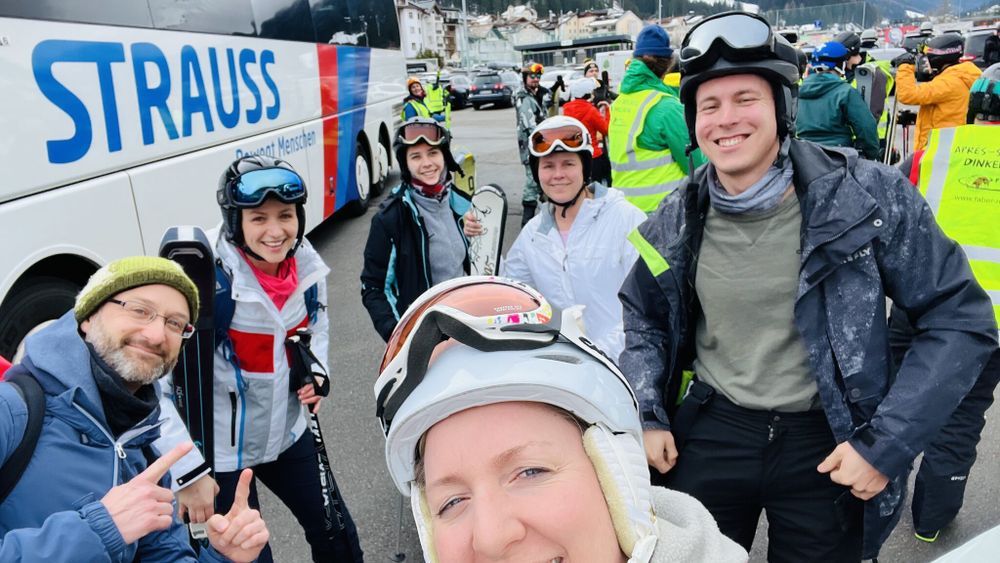 Good-humored BUSSE employees in ski outfits take a selfie in front of the coach.