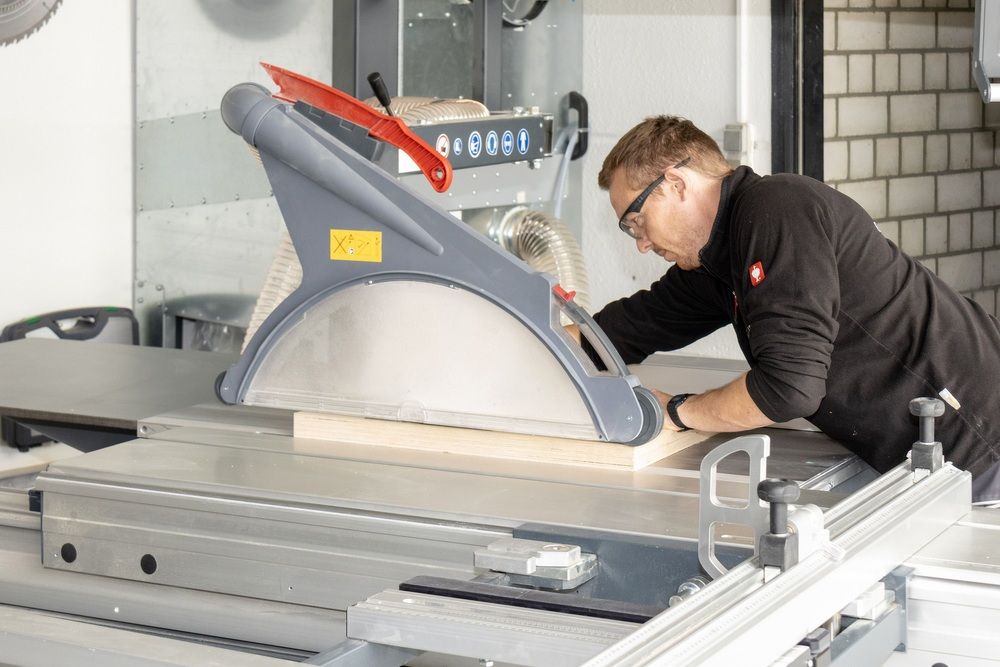 A man from the side, standing at a circular saw.