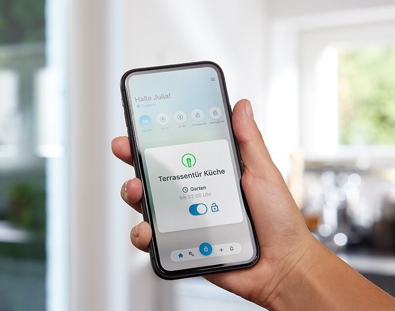 Hand holding smartphone with SIEGENIA HomeConnect app open.