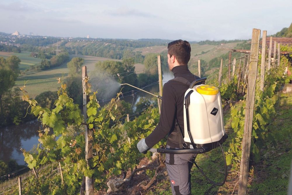Backpack sprayer being used by a man on a slope