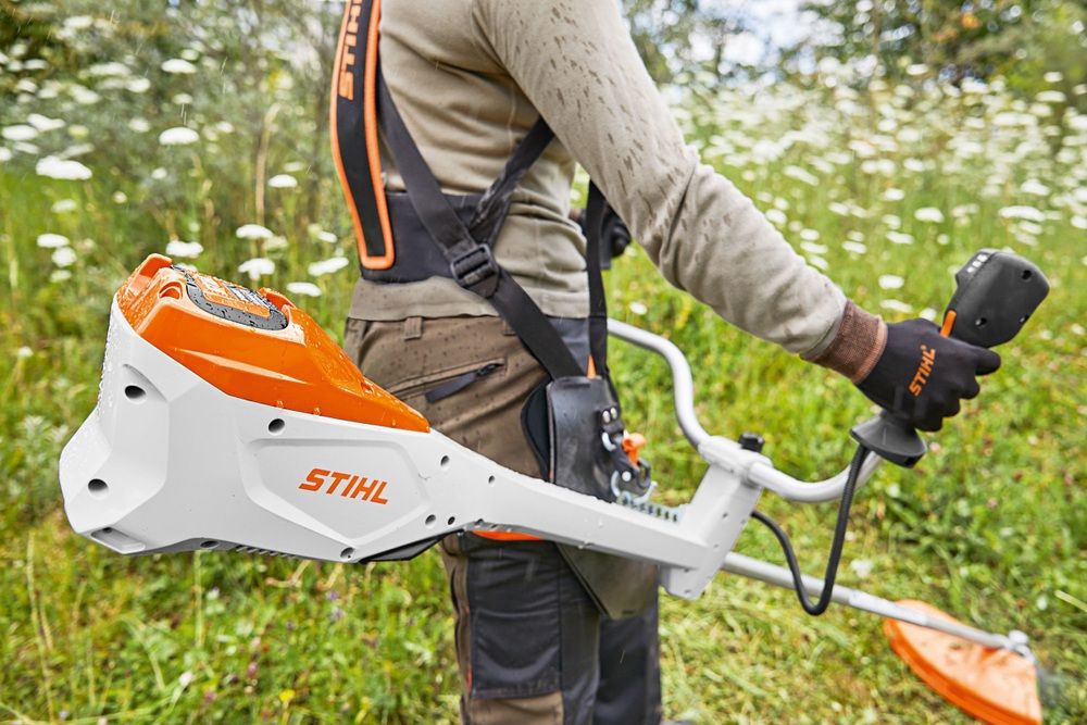 Person mowing meadow with Stihl FSA 135 brush cutter