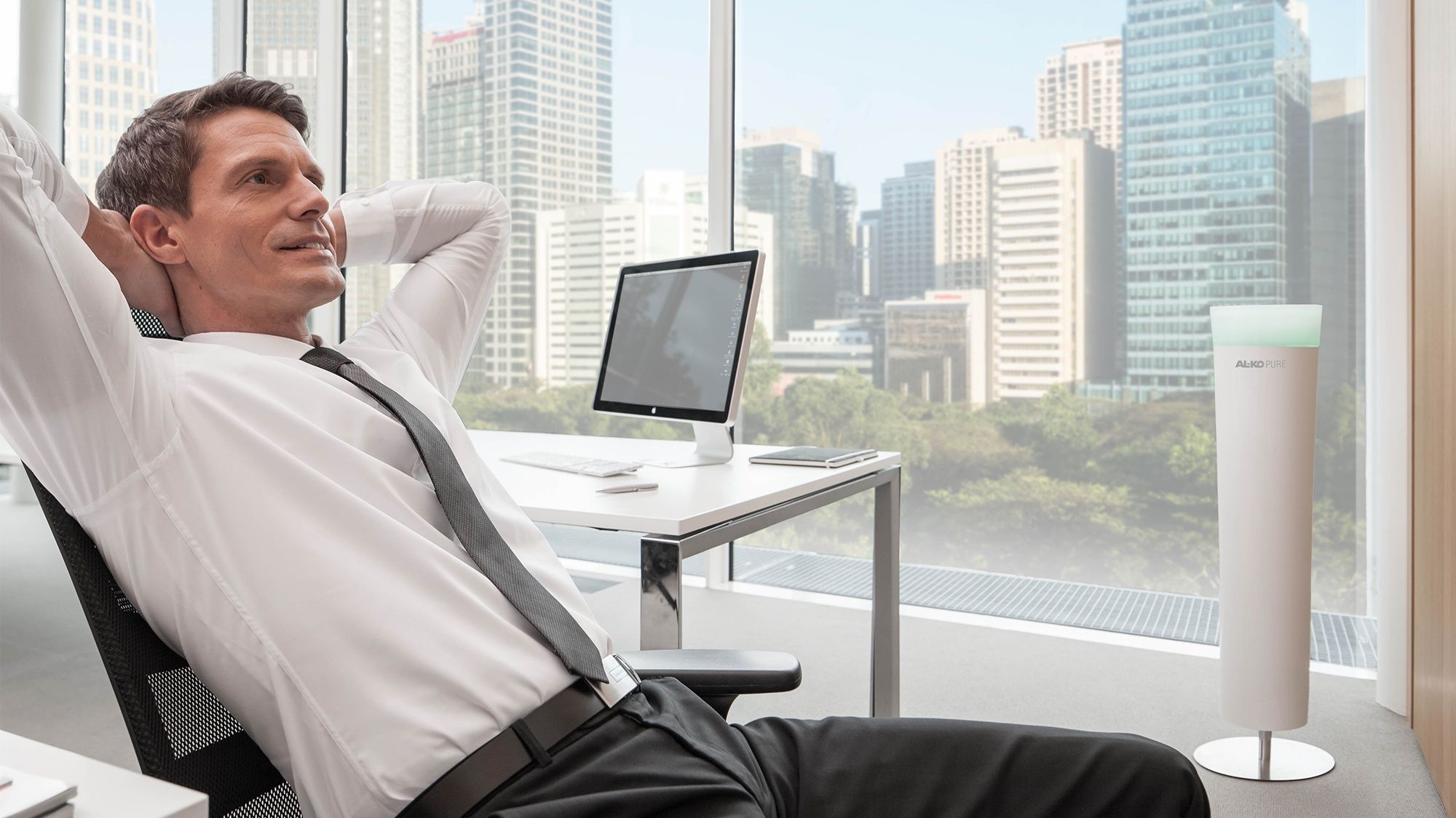Man sits relaxed in the office next to his room air filter