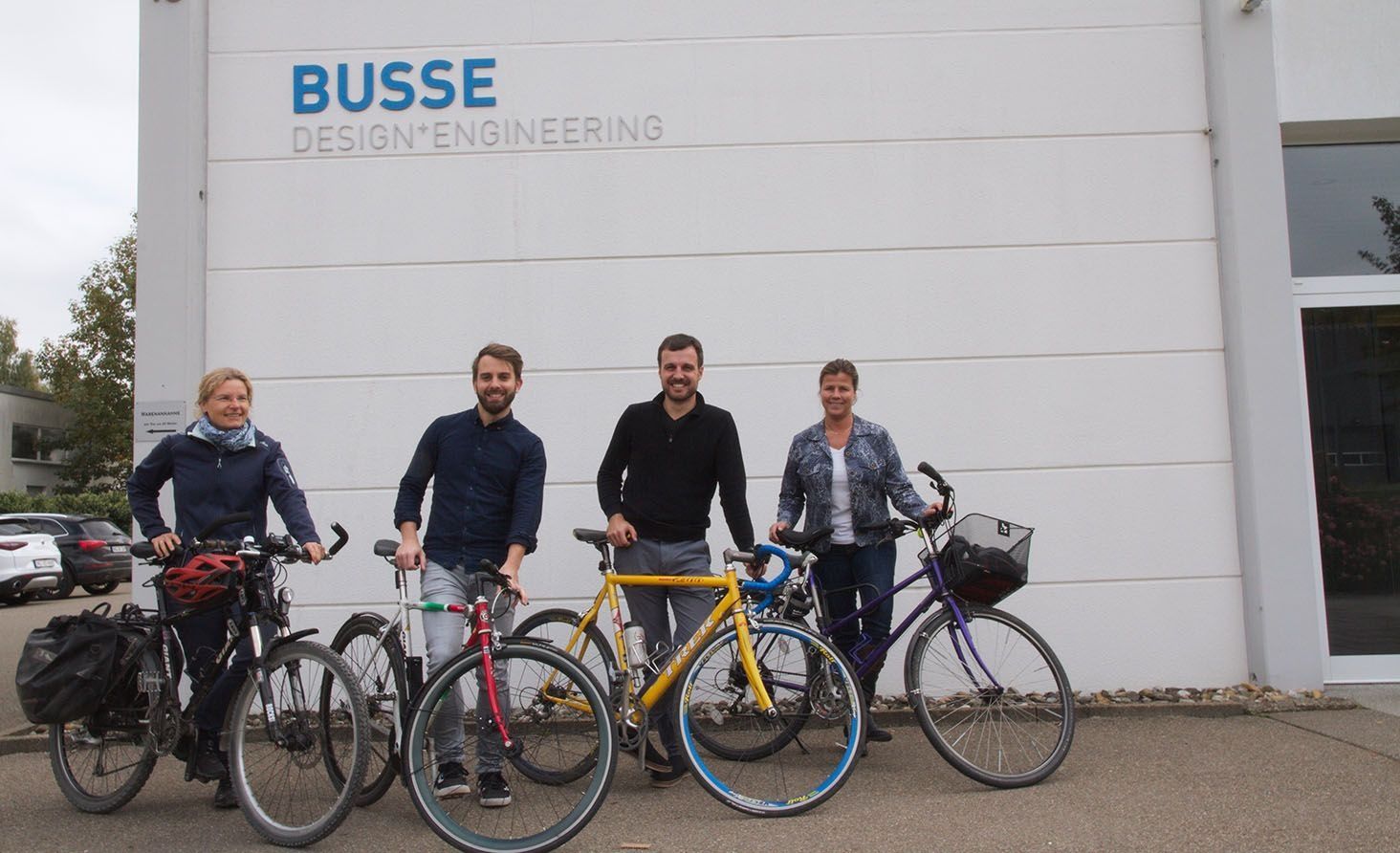 Employees stand in front of the Busse company building next to their bicycles
