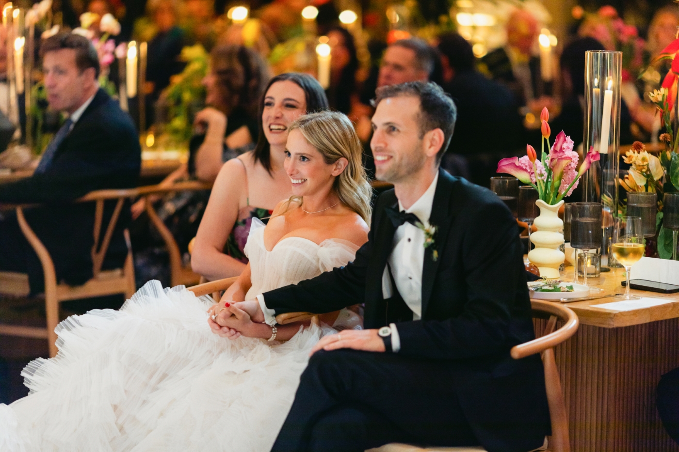 a bride and groom sitting together enjoying speeches at a downtown Los Angeles wedding reception in cathedral hall