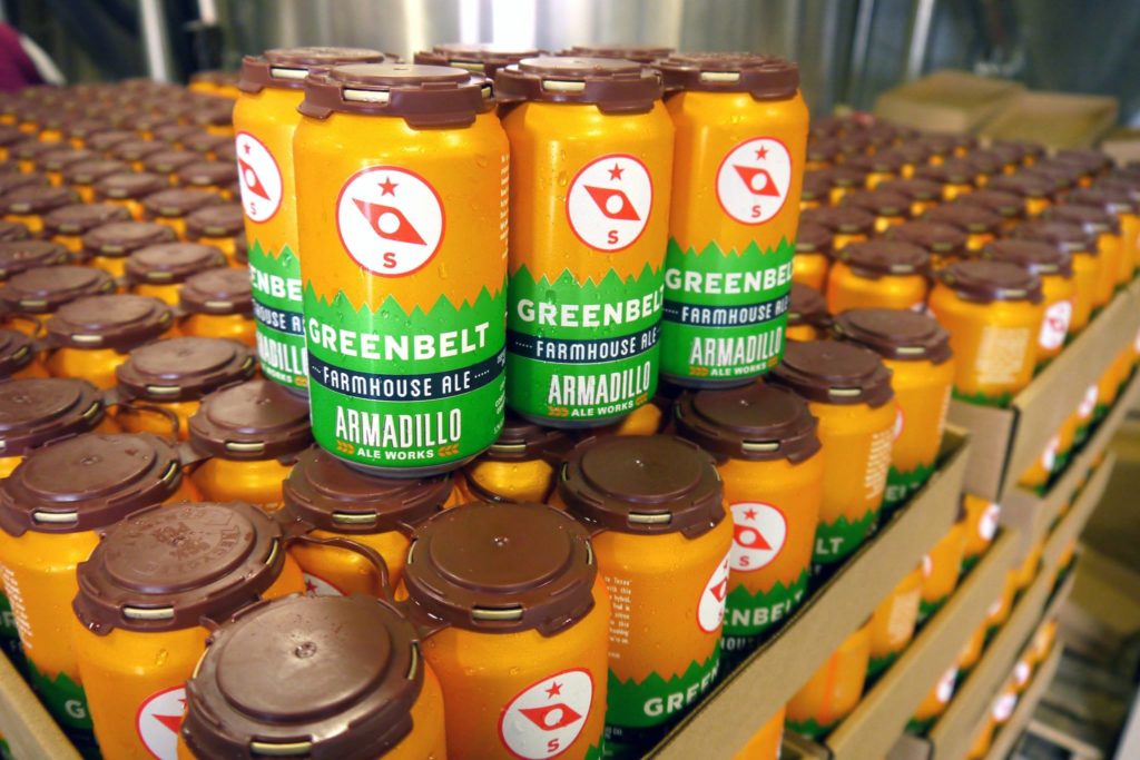 Several stacks of six-packs sit on top of each other, each branded with a golden, brown and green design.