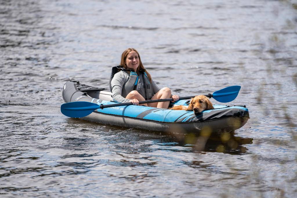 A woman kayaking with her dog in a lake