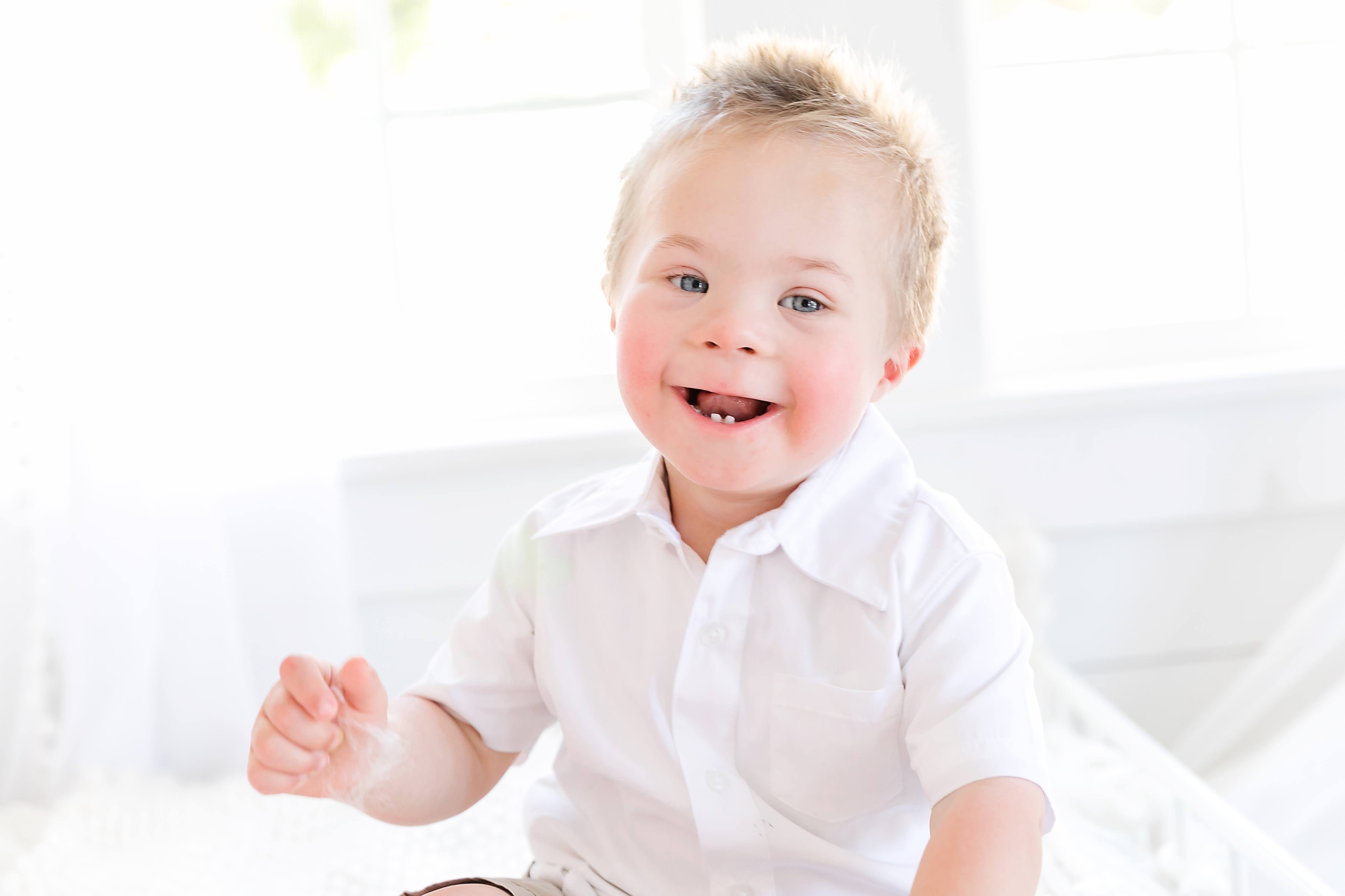 A young boy with down syndrome wearing a white shirt
