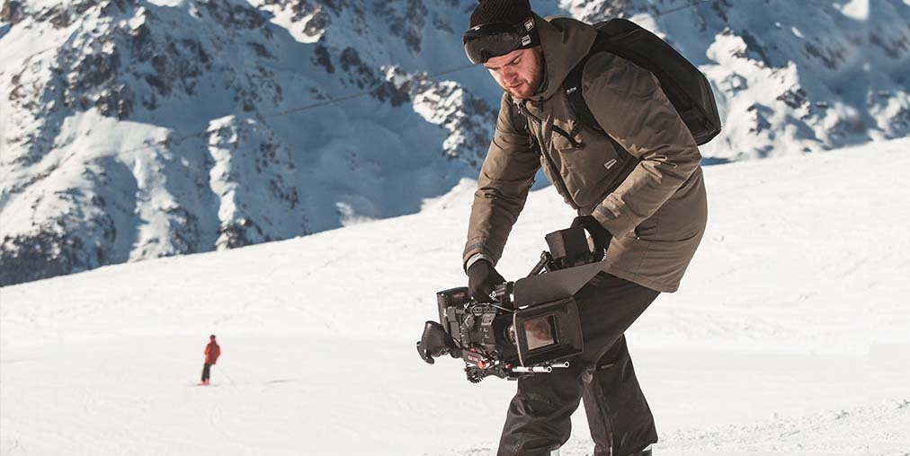 Camera man filming on a snowy mountain in the winter-wide