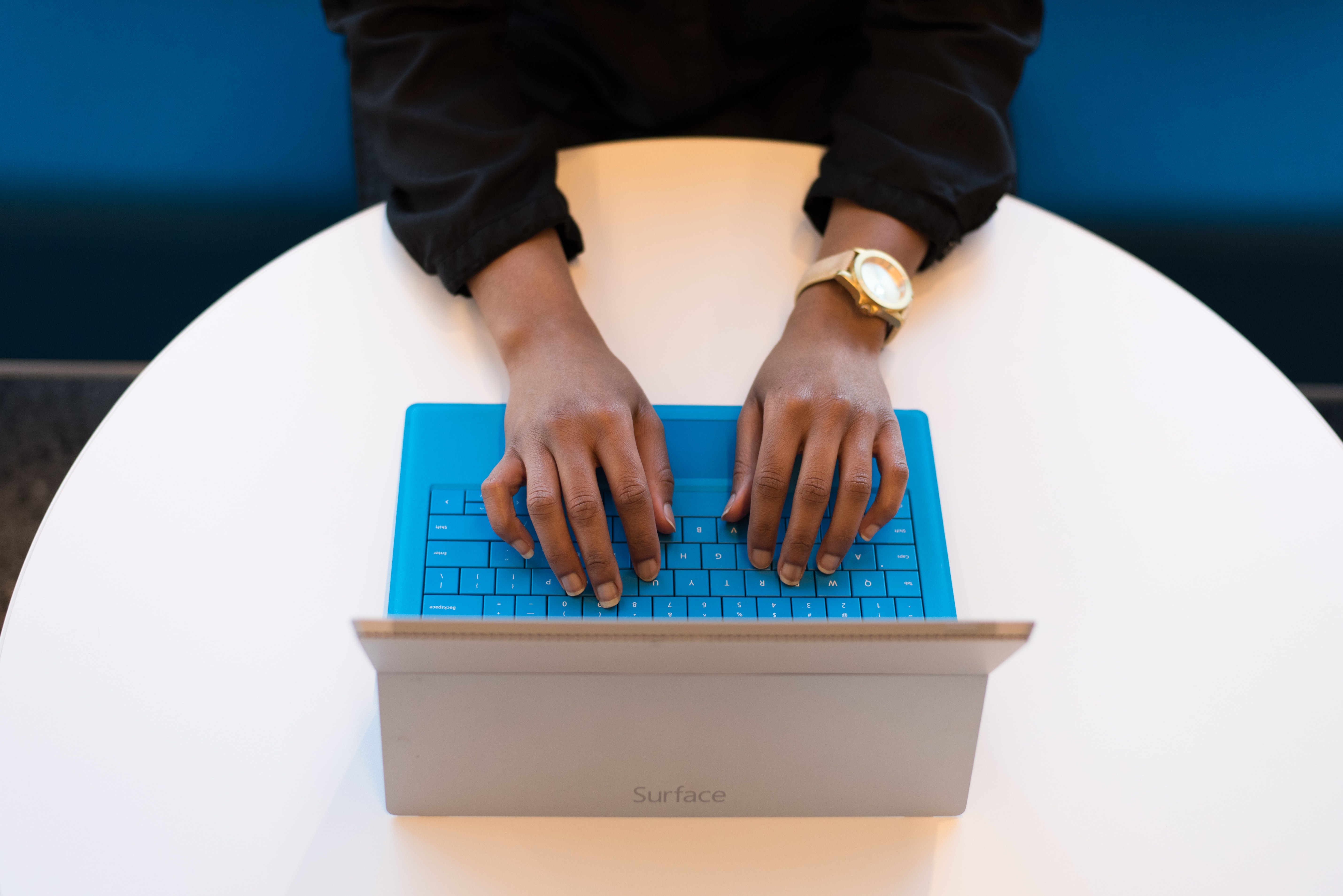 Business-Frau sitzt an rundem Schreibtisch und tippt auf Laptoptastatur