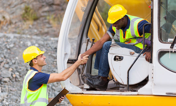 Two workers using heavy equipment