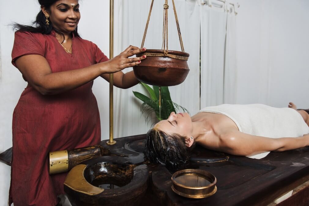 Indian woman performing Ayurvedic treatment on female client