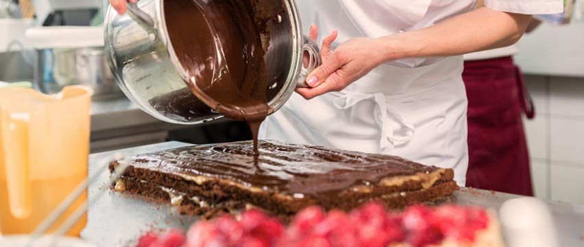 baker spreading chocolate over a cake