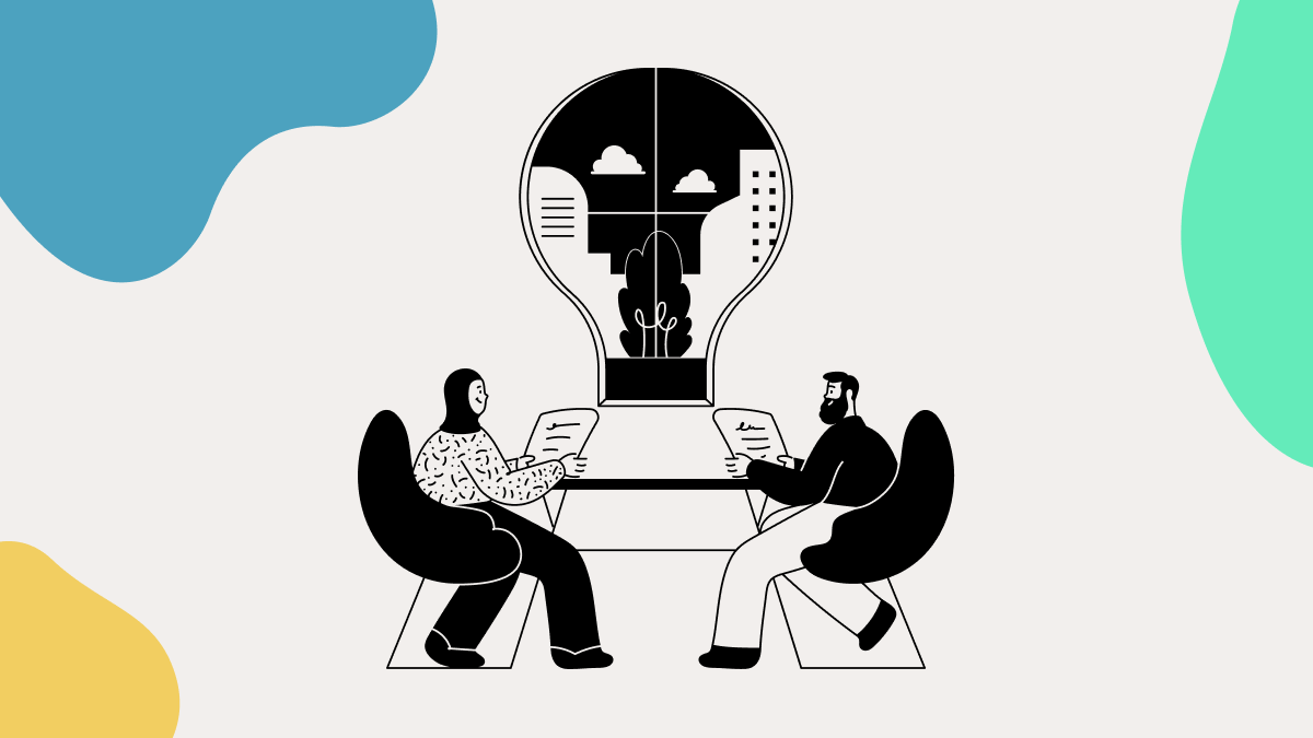 Two people sitting next to the giant bulb with a city inside of the bulb