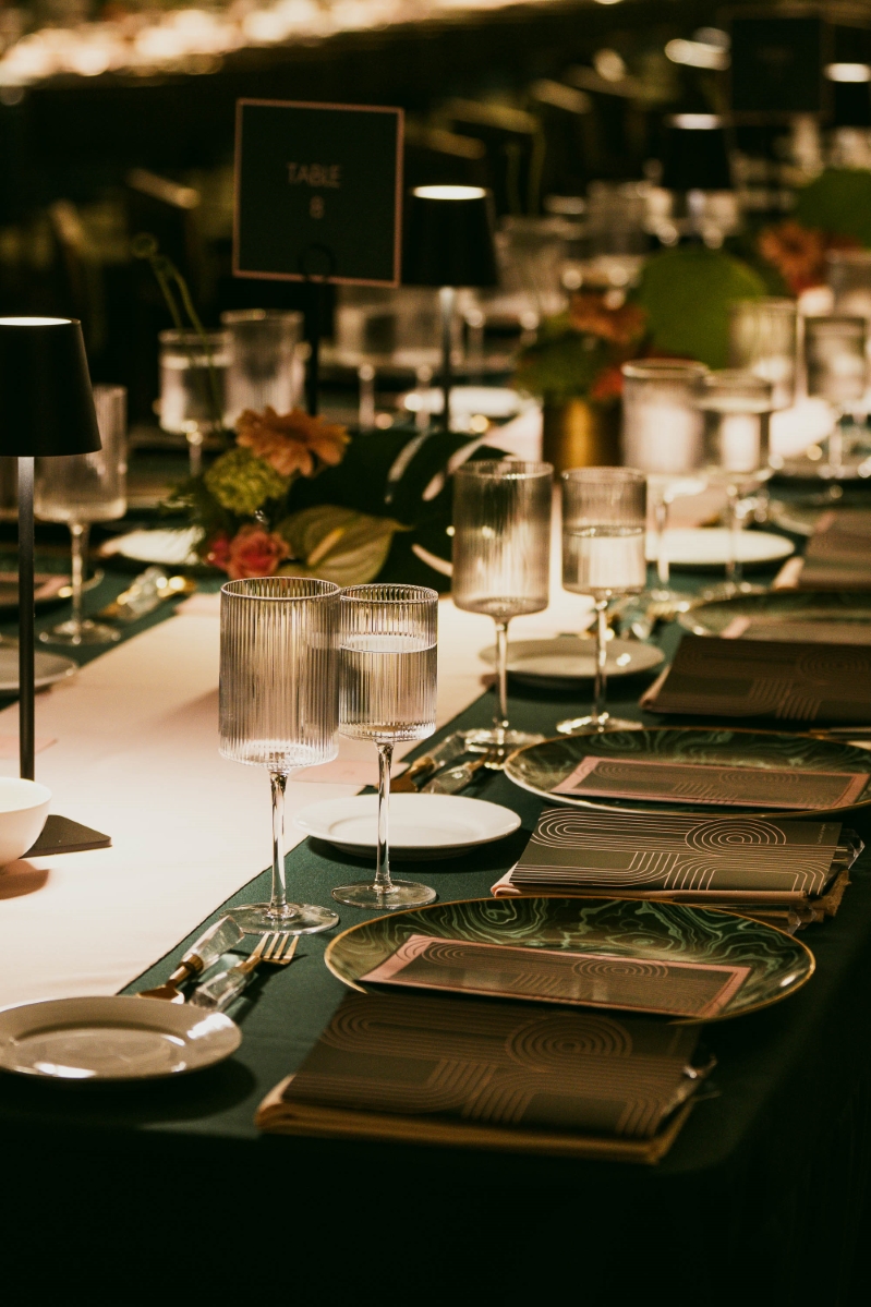 table settings with green tablecloths and menus. the tables are decorated with florals and square wine glasses, at an event at Vibiana in Downtown Los Angeles