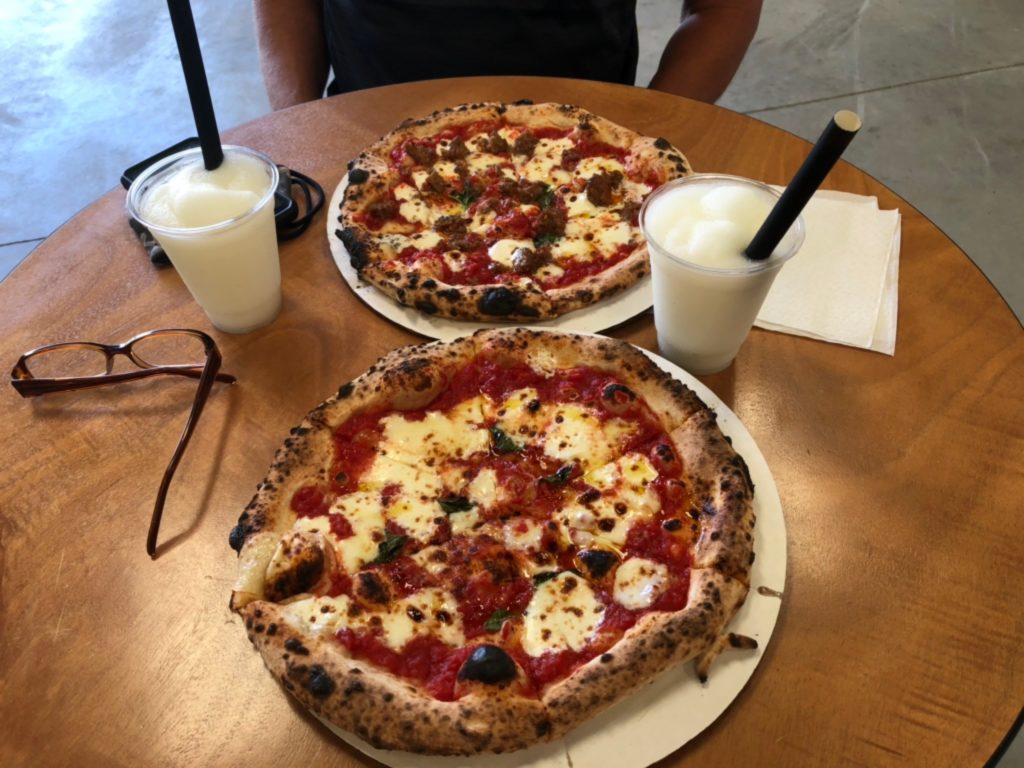 Two delicious wood-fired pizzas sit on a table at Broken Spoke Winery.