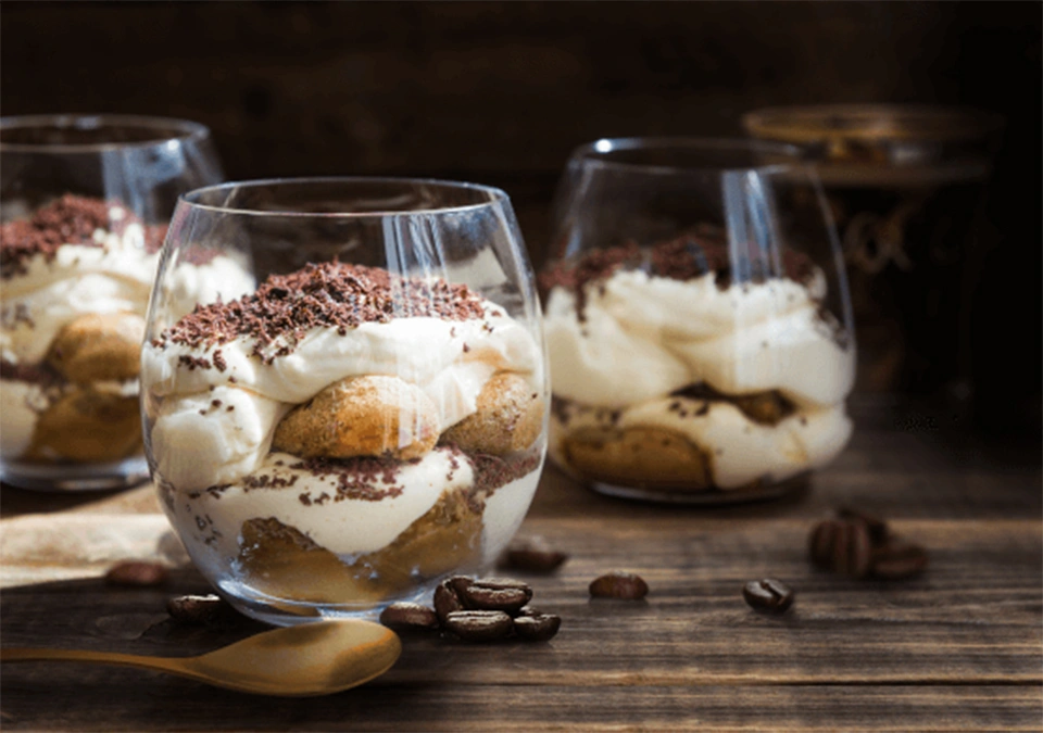 Three glasses of tiramisu infused with L'OR Espresso, on a table with coffee beans and a silver spoon.