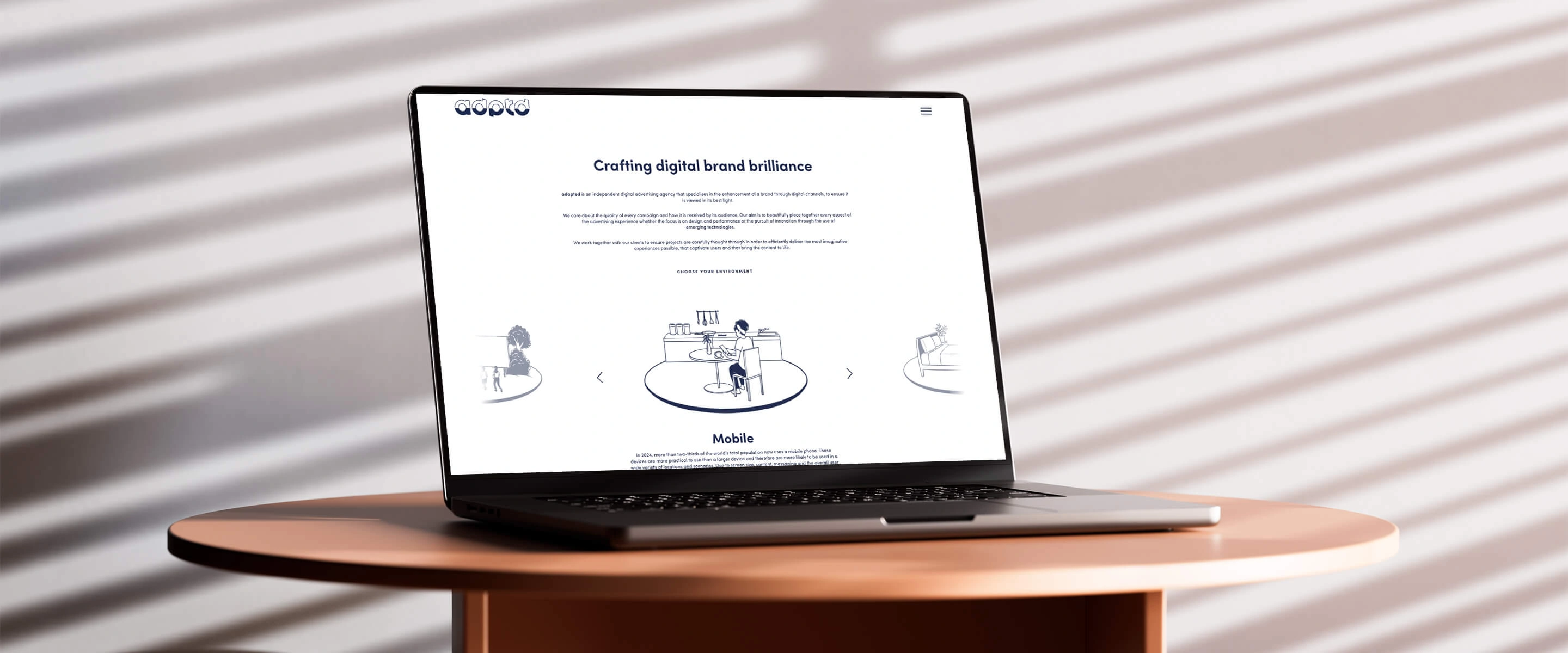 A laptop sat on a wooden table showing the adptd home page