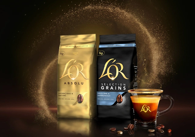 Two L'OR coffee bags and a glass cup of brewed coffee, surrounded by scattered beans on a dark background for a rich, premium feel.