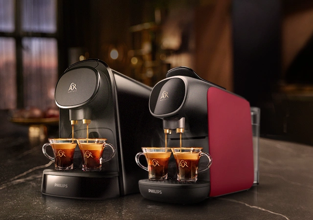 Two espresso machines brewing rich L'OR Espresso into elegant glass cups, filling the air with aroma.