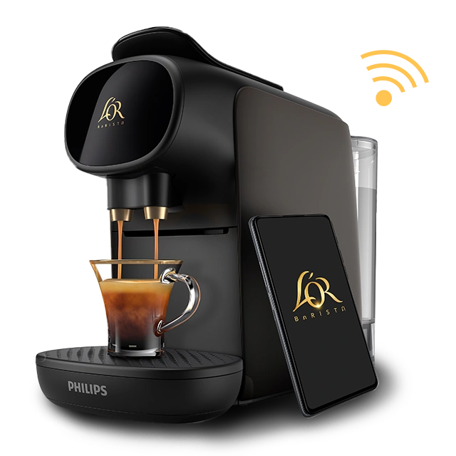 A Black coffee machine brews a rich L'OR Espresso beside a sleek smartphone, showcasing a perfect morning blend of technology and taste.