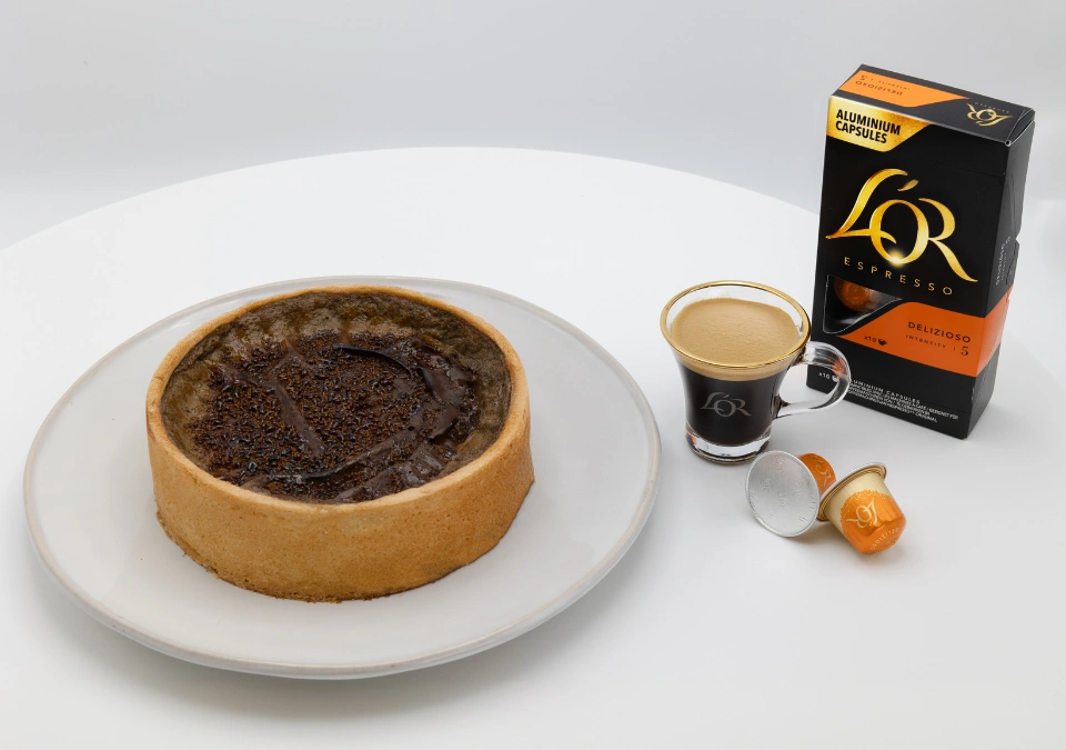 A coffee-flavored tart, perfectly paired with L'OR Espresso, sits enticingly next to L'OR espresso capsules and a freshly brewed cup of rich espresso.