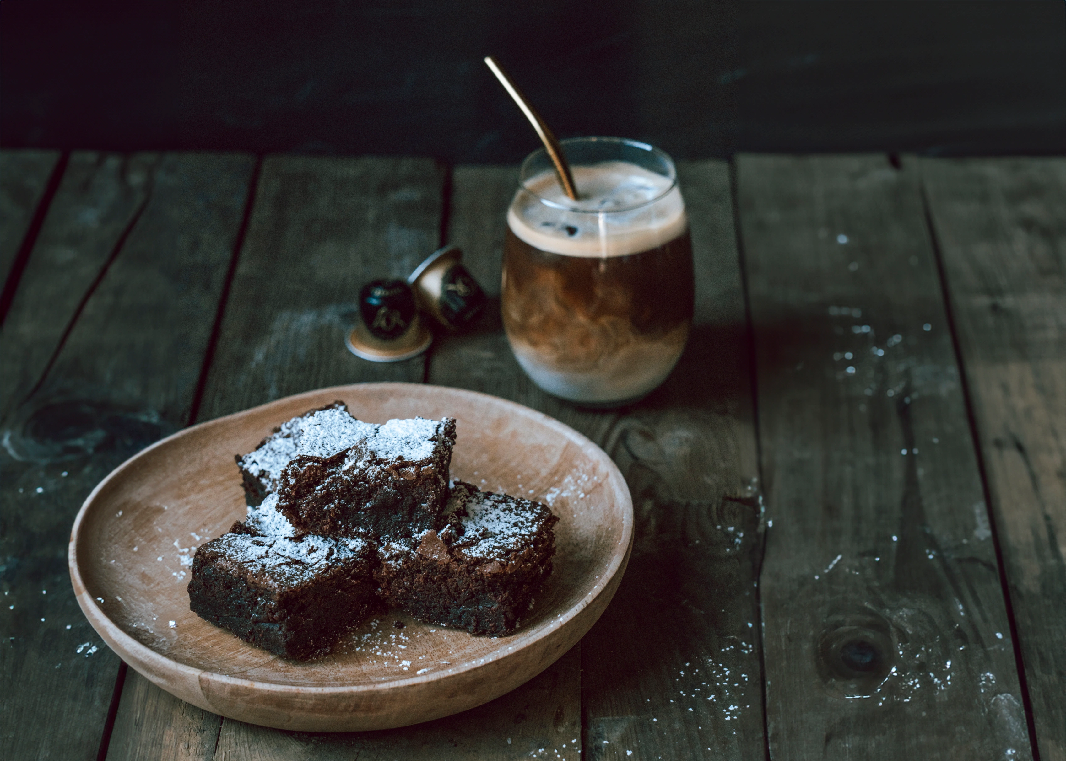 Rich chocolate brownies infused with L'OR Espresso, served on a wooden plate with iced coffee.