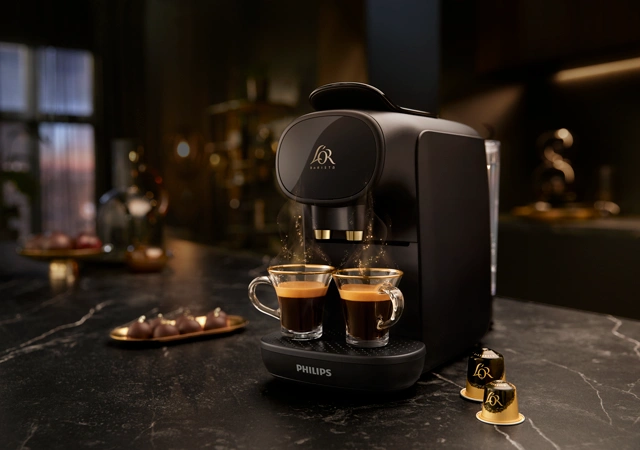 Coffee machine brewing espresso shots with L'OR capsules on a dark countertop, emphasizing luxury and aroma.