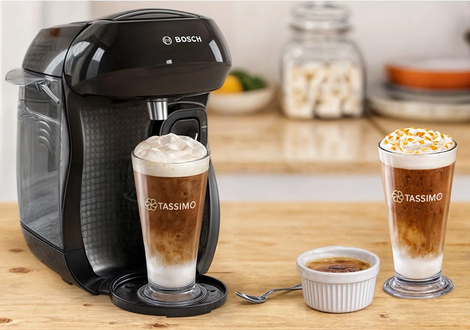 A Bosch coffee machine with TASSIMO sits beside two glasses of creamy coffee and a perfectly caramelized crème brûlée.