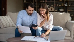 Casal com diversos contratos segurando uma calculadora