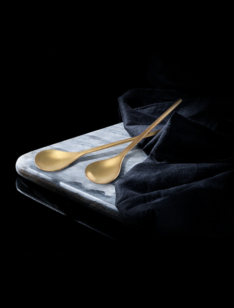 Golden spoons on a marble slab, with L'OR Espresso variants for a luxurious coffee theme.