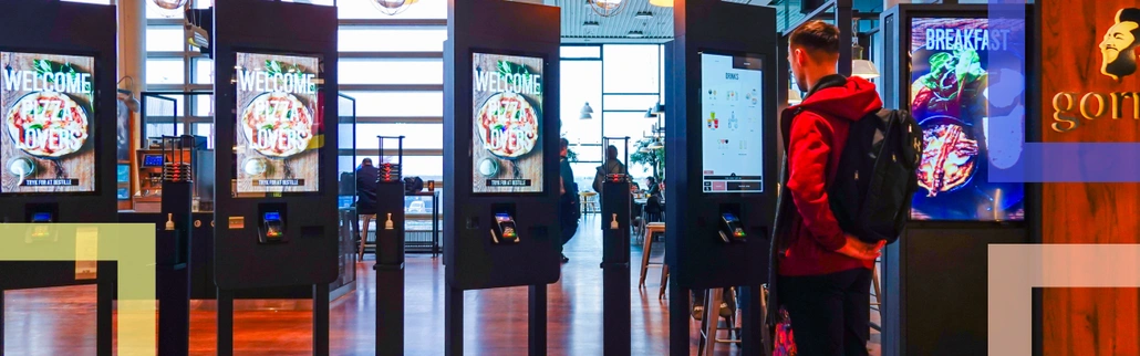 A person looking at food ordering kiosks