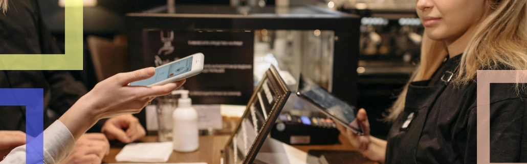 A waiter with a mobile payment terminal and a client paying with their phone