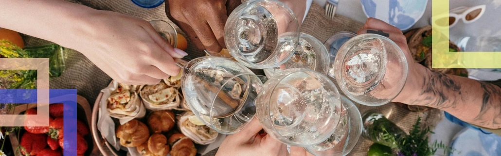 A few hands making toast with glasses of water above the dishes