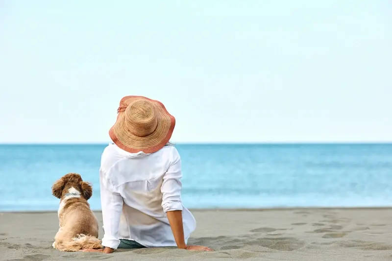 A woman sitting on a beach with her dog 