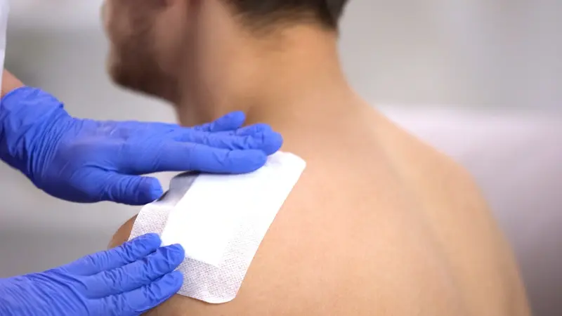 Wound being attended to on man's shoulder