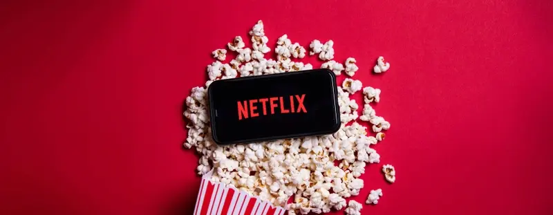 Phone lying on spilled popcorn with Netflix logo on
