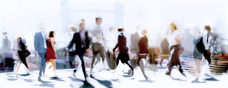 Blurry image of commuters walking past each other on the way to work