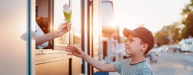 child getting ice cream cone from an ice cream van