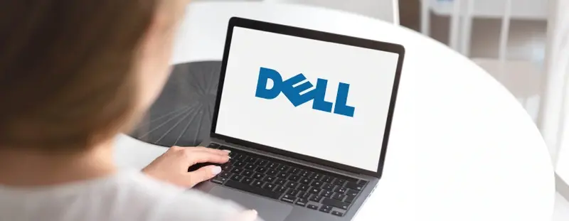 Woman using laptop, the screen has the Dell logo showing