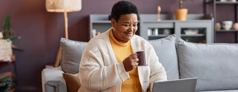 Woman drinking hot drink and on laptop