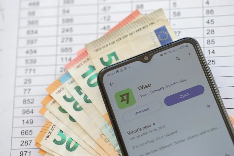 Wise app on background of cash notes