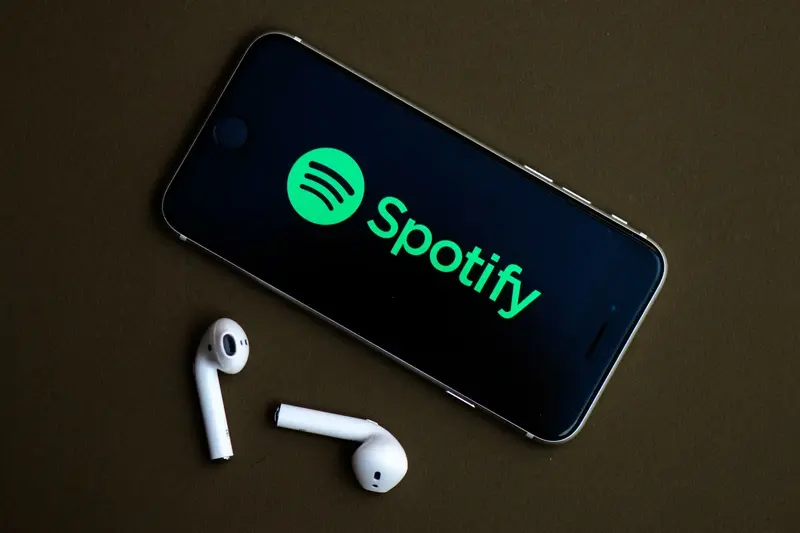 Spotify displaying on a smart phone, logo and air pods