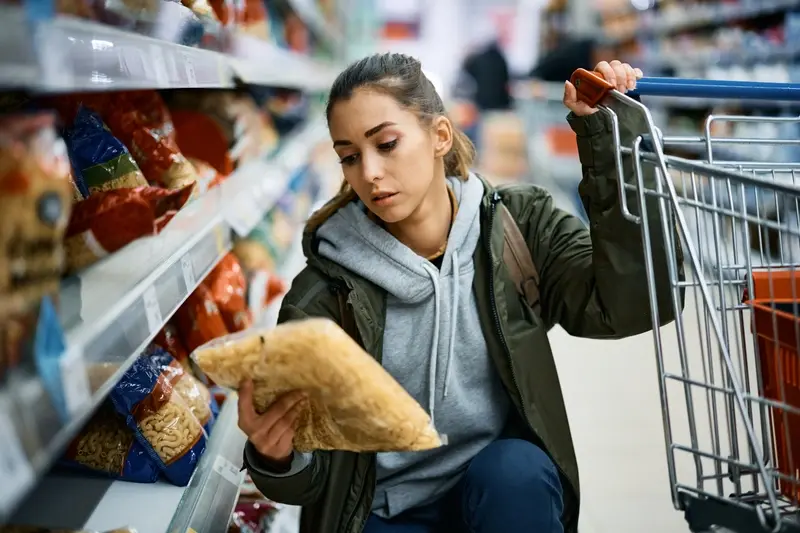 Shopper checking price of pasta