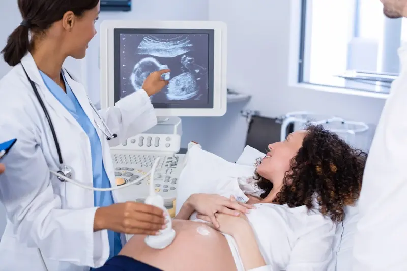 Pregnancy ultrasound scan with baby image on monitor
