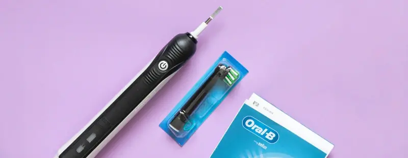 Oral B electric toothbrush against a purple background