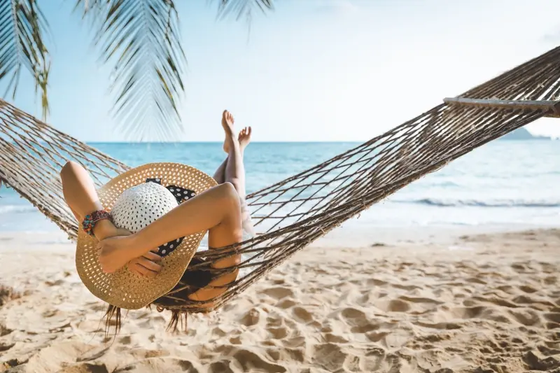 Holidaymaker lying in a hammock on the beach