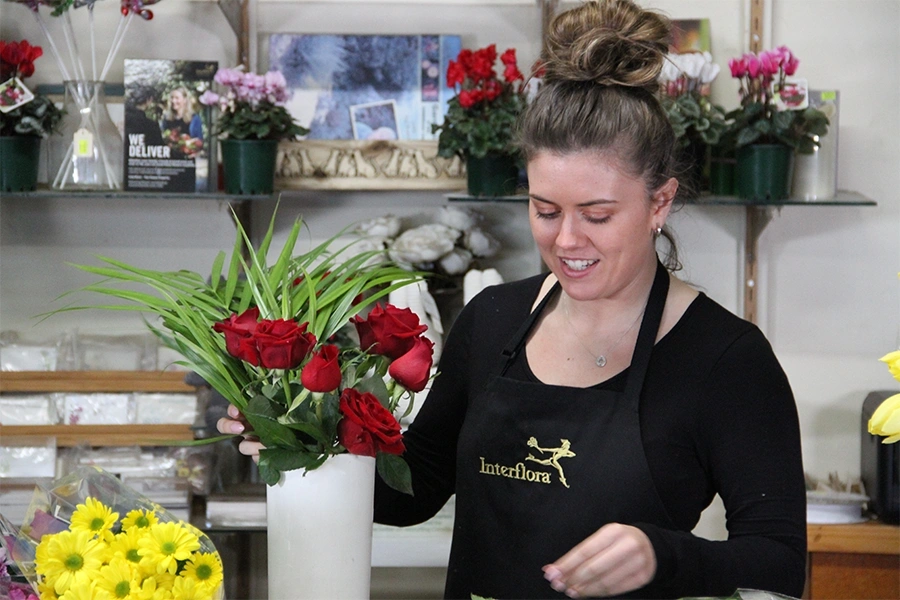 Interflora florist caring for an arrangement of roses.