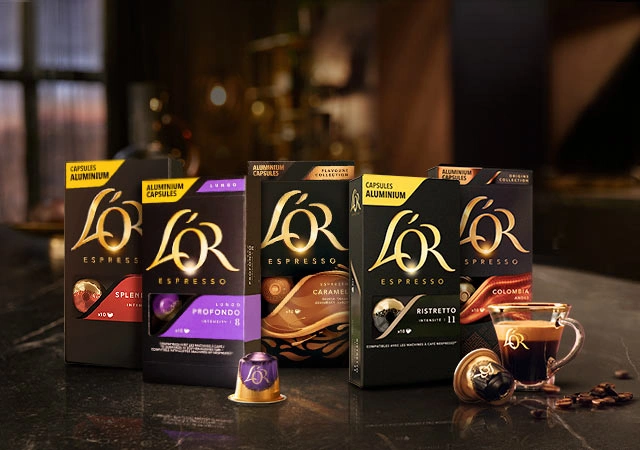 L'OR coffee capsules arranged on a dark table with various variants and a coffee cup for an inviting ambiance.