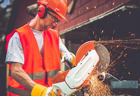 Worker using steel cutoff saw farm equipment