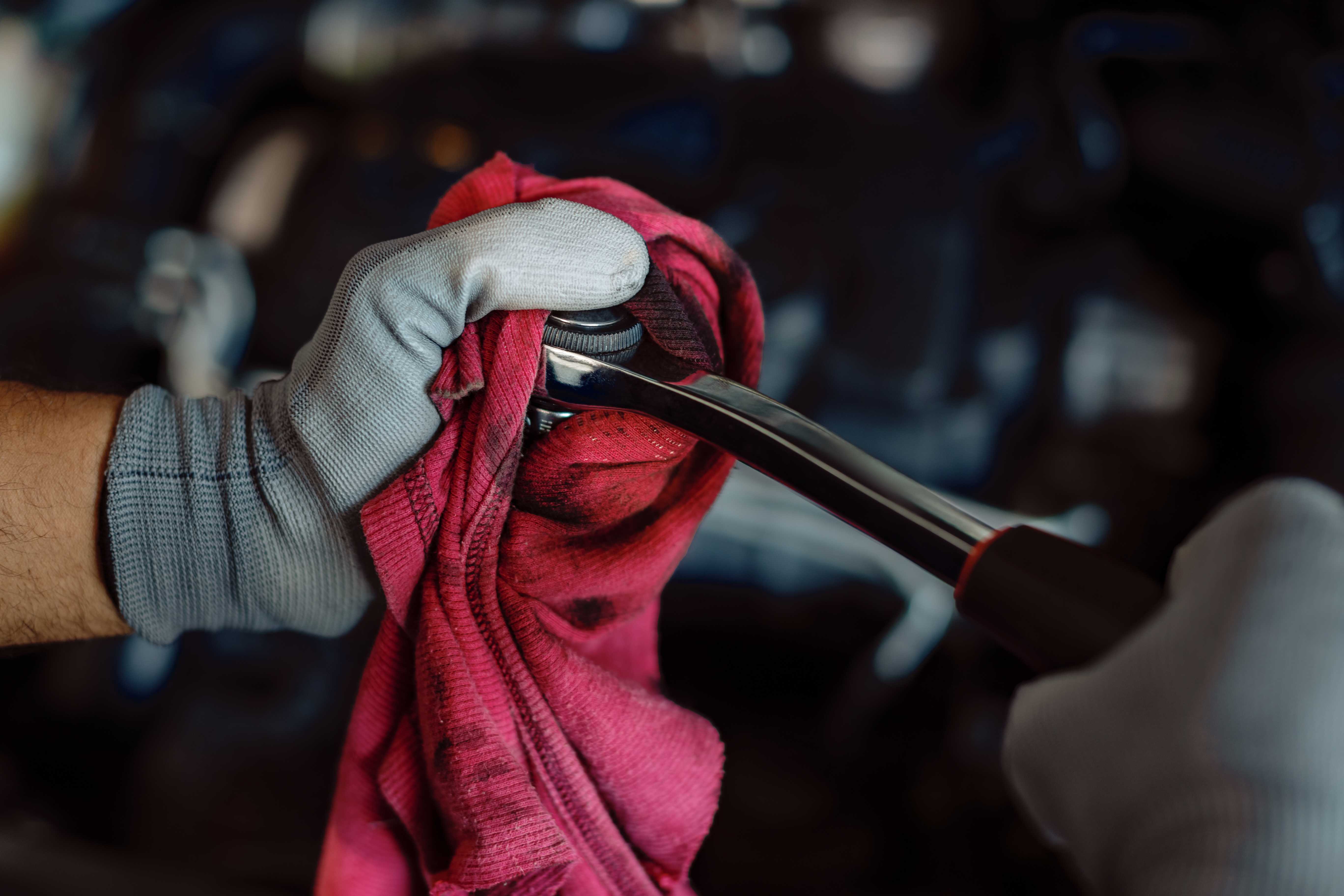 Close-up of a mechanic cleaning wrench with a cloth in auto repair shop